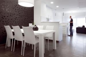 un uomo in piedi in una cucina con tavolo e sedie bianchi di 08028 Apartments a Barcellona