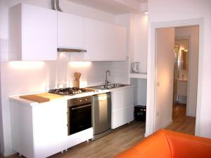 een keuken met witte kasten en een fornuis met oven bij Bright apartment in Cagliari