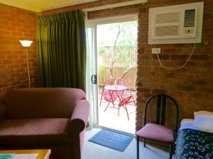 a living room filled with furniture and a window at Inverloch Central Motor Inn in Inverloch