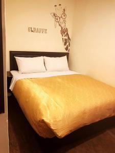 台東市にあるHoliday Business Hotelのキリンが壁に掛けられたベッドルームのベッド1台