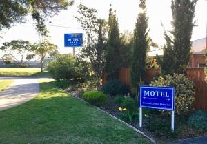 ein blaues Motelschild in einem Hof neben einer Einfahrt in der Unterkunft Inverloch Central Motor Inn in Inverloch