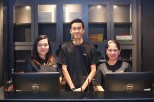 Un homme et trois femmes debout devant les ordinateurs portables dans l'établissement Avenue J Hotel, Central Market, à Kuala Lumpur