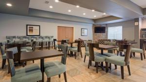 uma sala de jantar com mesas e cadeiras e uma televisão em Best Western Plus Sand Bass Inn and Suites em Madill
