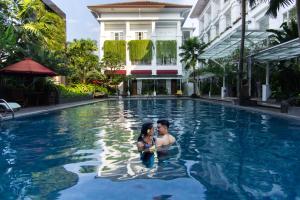 a man and a woman standing in the water in a swimming pool at Gallery Prawirotaman Hotel in Yogyakarta