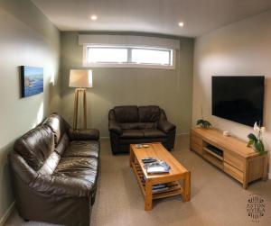 a living room with a couch and a tv and a table at Aston Road Villa Bed & Breakfast in Waikanae