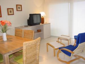 sala de estar con mesa, TV y sillas en Apartamentos Rodamar, en L'Estartit