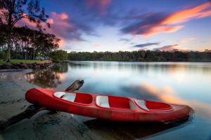 - un canoë rouge assis sur la rive d'un lac dans l'établissement Solitary Islands Resort, à Wooli