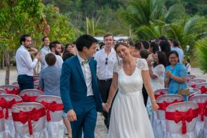 eine Braut und ein Bräutigam, die bei ihrer Hochzeit den Gang entlang gehen in der Unterkunft Palm Beach Bungalow Resort in Koh Rong