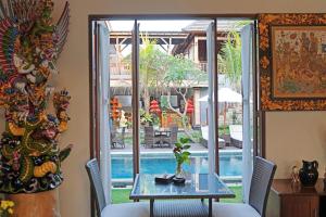 ein Esszimmer mit einem Tisch und Poolblick in der Unterkunft Lebak Bali Residence in Canggu