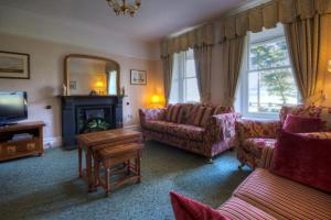 a living room with couches and a tv and a mirror at Gwrach Ynys Country Guest House in Harlech