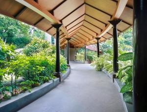 a covered walkway in a garden with plants at Uday Suites - The Airport Hotel in Trivandrum