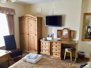 a bedroom with a bed and a dresser with a television at The Northdale Hotel Ltd in Skegness