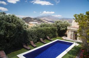 einen Pool in einem Garten mit Stühlen und einem Haus in der Unterkunft Cortijo Salobrena in Salobreña