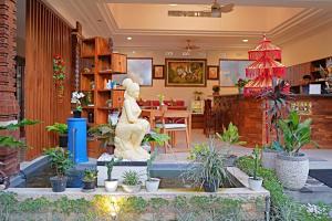 een lobby met een standbeeld in het midden van planten bij Lebak Bali Residence in Canggu