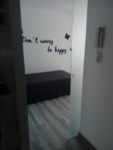 a bedroom with a door with a sign that reads dont worry be happy at Jazmines in Santiago de la Ribera