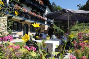 un grupo de personas sentadas en una mesa bajo un paraguas en Gästehaus Marlies Keutschach am See en Keutschach am See