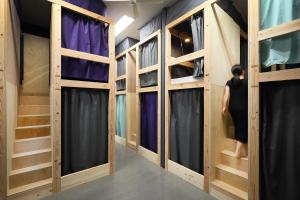 a woman is walking through a room with wooden bunk beds at Iruka Hostel in Toyama