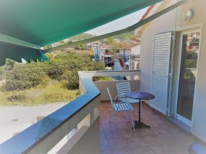 a balcony with a table and a chair on it at Apartments Vrtlici in Stara Novalja