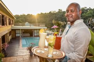 a man holding a table with drinks on it at Bambuu Lakeside Lodge in Hazyview