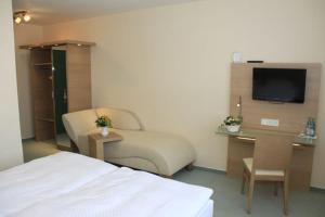 a hotel room with a bed and a desk and a tv at Wehrmann-Blume in Wunstorf