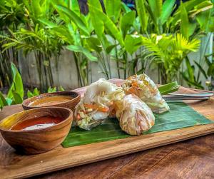 een bord eten op een houten tafel met dipsaus bij Green Garden Lembongan Yoga Spa and Holistic Healing Center in Nusa Lembongan