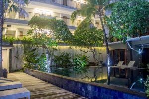 a hotel with a fish pond in front of a building at Transera Kamini Legian Hotel in Legian