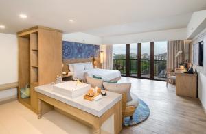 a living room with a bed, table and a window at Eastin Ashta Resort Canggu in Canggu