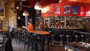 un hombre parado en un bar en un restaurante en Charlie Rockets Youth Hostel, en Brujas