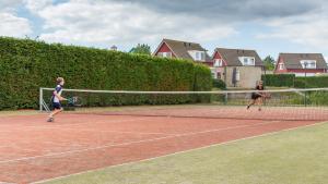 Dos personas jugando al tenis en una cancha de tenis en Antibes 252 - Kustpark Village Scaldia, en Hoofdplaat