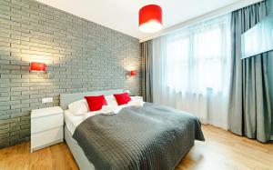 1 dormitorio con 1 cama con almohadas rojas y pared de ladrillo en Apartamenty Sun & Snow Residence Karpacz en Karpacz