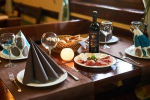 einen Holztisch mit Teller mit Speisen und Weingläsern in der Unterkunft Hotel Laguna in Podgorica