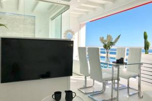 una sala da pranzo con tavolo e grande TV a schermo piatto di Loft del Mar - Charming luxury apartment at La Roca a Torremolinos