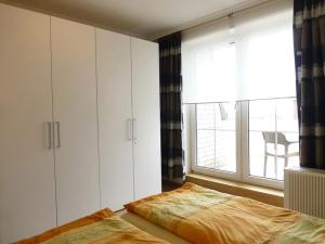 a bedroom with white cabinets and a bed and a window at Villa Marina Wangerooge in Wangerooge