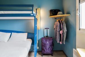 a bedroom with a bunk bed with a suitcase and a hat at ibis budget Marne la Vallée Val d'Europe in Montévrain
