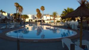 a large swimming pool with palm trees and buildings at Puerta del Sol in Caleta De Fuste