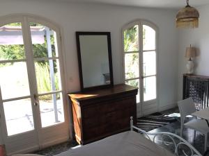 a room with a mirror on a dresser and two windows at La maison du lac in Auvers-sur-Oise