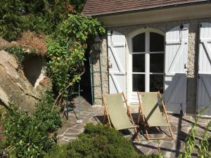 two chairs sitting on a patio in front of a house at La maison du lac in Auvers-sur-Oise