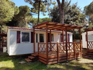 a tiny house with a porch and a deck at Victoria Mobilehome in Centro Vacanze San Francesco in Duna Verde