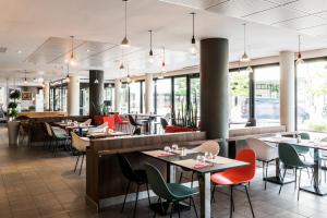 a restaurant with tables and chairs and windows at ibis budget Marne la Vallée Val d'Europe in Montévrain