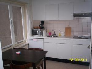 - une cuisine avec des placards blancs, une table et un évier dans l'établissement Hotel Noordzee, à Zandvoort