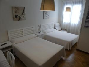 a hotel room with two beds and a chair at Hostal America in Madrid