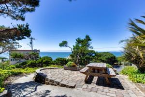 a picnic table on a stone patio with the ocean in the background at Wycliff Beach Condo in Lincoln City