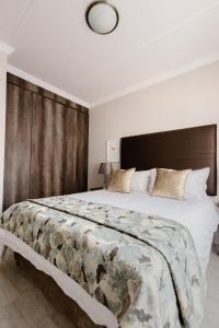 a bedroom with a large bed with a wooden headboard at Kyalami Creek in Midrand