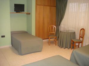 um quarto com uma cama, uma mesa e cadeiras em Hostal Serpol em Palencia