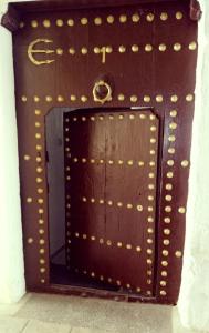 a brown door with gold rivets on a wall at Maison Saadia in Rabat