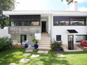 una casa blanca con césped delante en Bonvalot Guest House, en Paço de Arcos