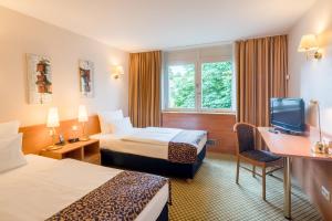 Best Western Plus Hotel Fellbach-Stuttgart في فيلباخ: غرفه فندقيه سريرين وتلفزيون