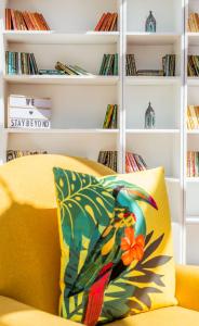 een gele bank met een kleurrijk kussen voor een boekenplank bij The Queen Edith Place - Lovely 6BDR Home in Secluded Area in Cambridge