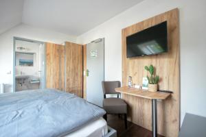 a bedroom with a bed and a television on a wall at Hotel Birkensee in Hannover
