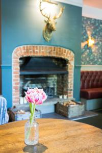 The Dundas Arms في Kintbury: وردة في مزهرية على طاولة مع موقد